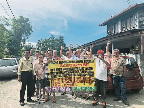  增江南區淡巴漢木屋區居民週三（14日）拉橫幅促請吉隆坡市政局向發展商“施壓”盡快展開工程，左是余保憑。 