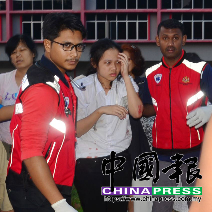 醫務人員扶持左手輕傷的姐姐,準備送院治療。