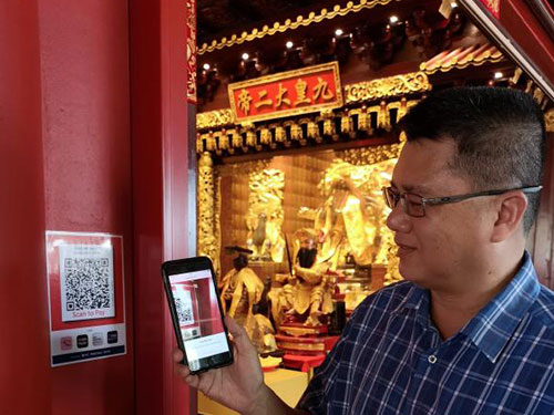 龍南殿總務張祖財示範如何使用手機掃描QR碼進行交易。