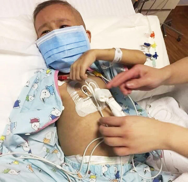 目前正在接受化疗的游梓彬,身上插满管子,脸上露出痛苦的表情。(受访者提供)