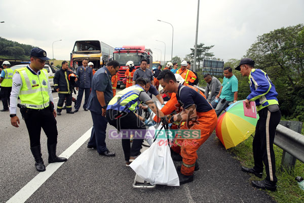 消拯员及警员一起把女死者的遗体包裹后，准备送往医院太平间。