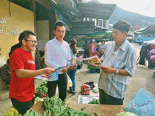 李政贤（左）到甘榜拉惹早市，派发传单给村民。