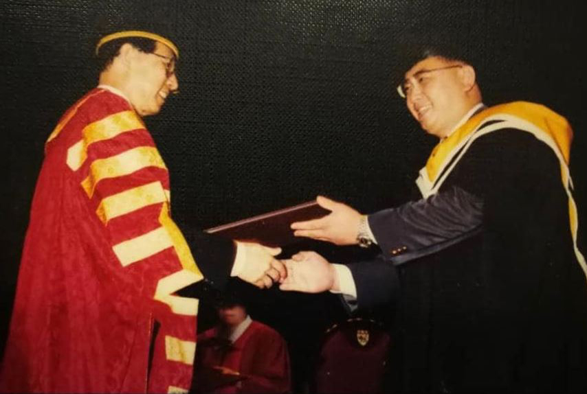 魏家祥（右）于1996年，从已故王鼎昌手中接过硕士文凭。