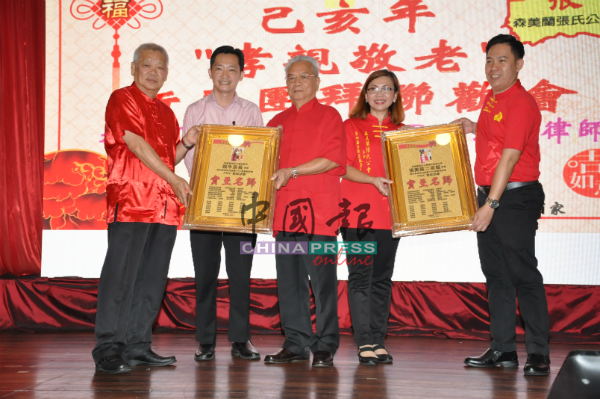 张生（左）和张准征（右）在谢琪清（左2起）见证下，移交贺牌予在2018年荣膺森州最高统治者殿下封赐PMC勋衔的张牛和张美霞。