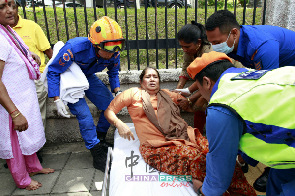 一名中年妇女申诉头晕，由民防局救护人员抬离现场。