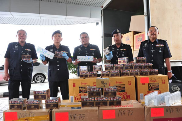 警方成功起获总值11万9000令吉的8430包各种品牌的走私香烟，左2为卓明耀。