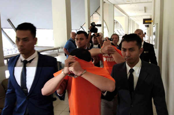涉嫌索取贿款的两名嫌犯（橙衣者）被反贪会官员押上法庭申请延扣。