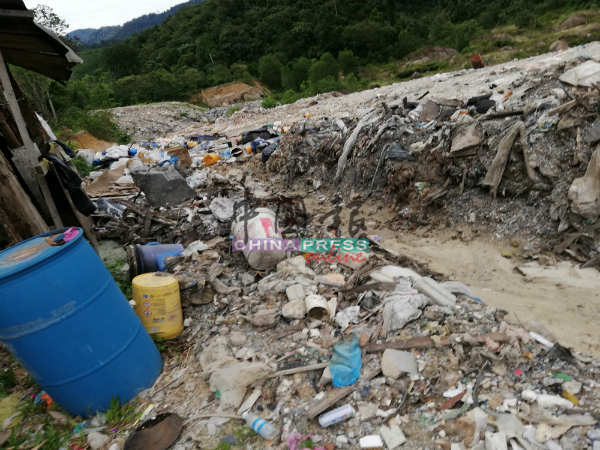 大量的建筑废料，包括石块、桶被运送到非法垃圾场。