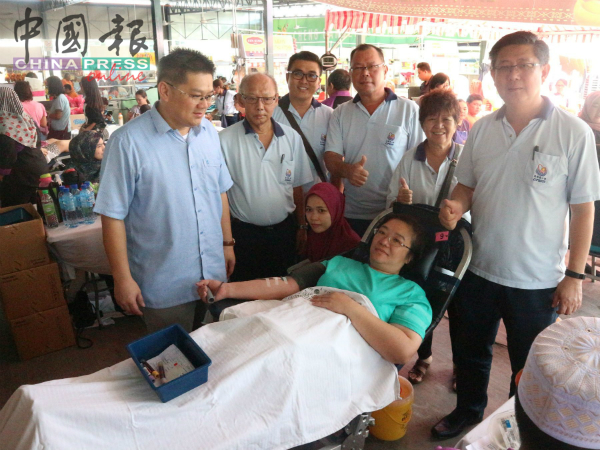 林万锋（左）与甲马华志工团成员为捐血者加油打气，右为杨焕源。