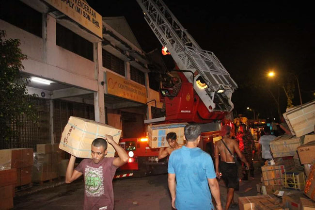 火势被扑灭后，员工立即搬运未被大火烧毁的货物离开。