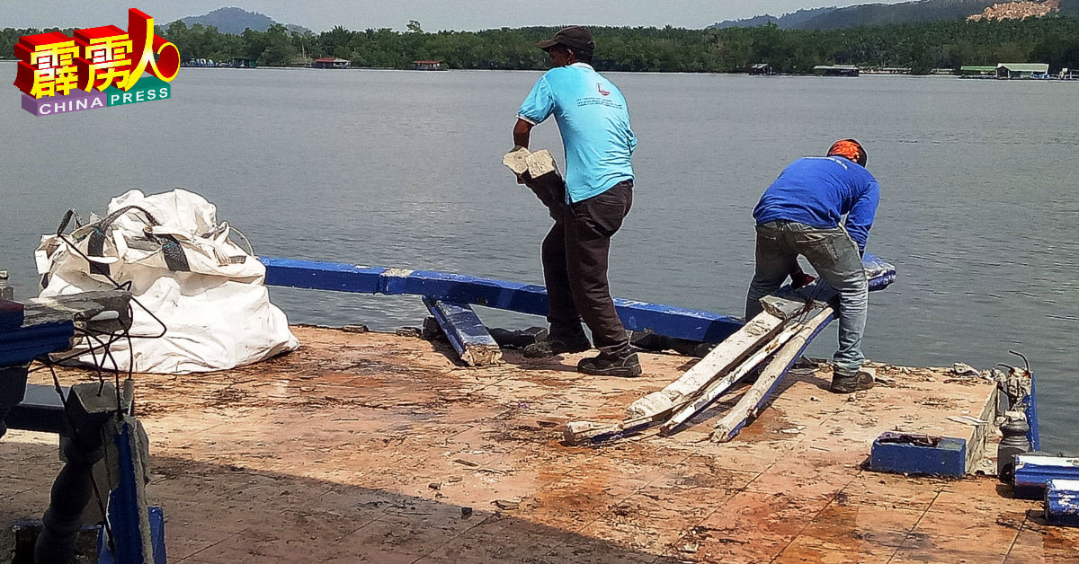 员工清理码头上的水泥柱和木板残骸。
