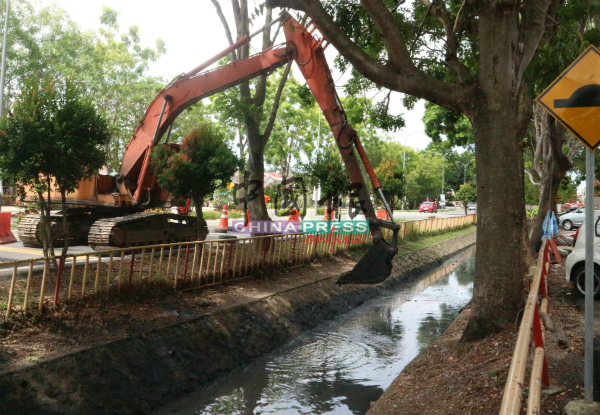 坭机在挖掘默迪卡再也大路排洪沟的淤泥，让沟水可以顺畅流动。