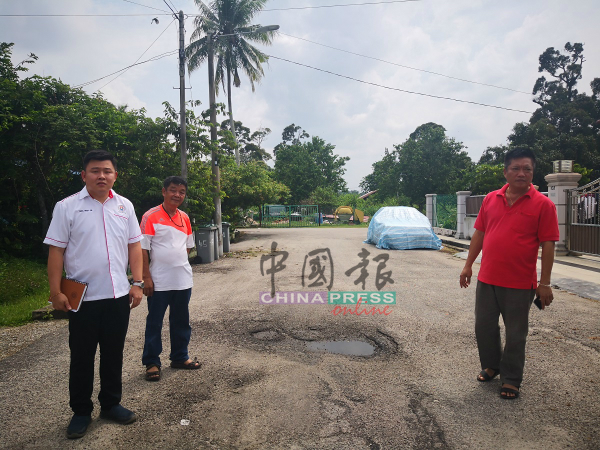 黄明利（右起）邓泽荣展示新村破烂不堪的道路。左为张文杰。