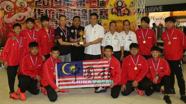 郑国球（右5）颁发奖杯给吴建培（左4），祝贺马六甲高峰龙狮体育会舞龙队旗开得胜，荣获世界冠军。 