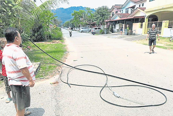 淡边运达花园居民无奈望着遭扯断并掉落车路的电缆。