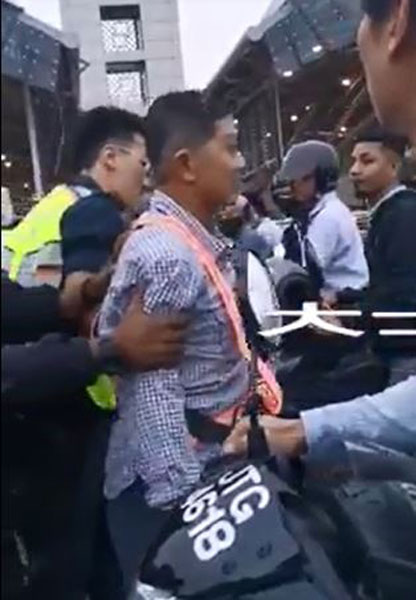 华裔男子疑不支晕倒后，被在场的官员搀扶离开现场。