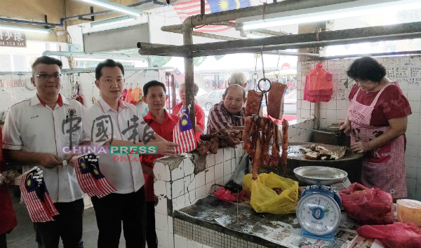 谢琪清（左2）亲自在猪肉摊位插上国旗，迎接国庆日的到来，左为李汉强。