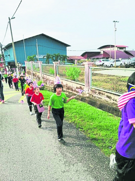 淡边新村华小学生挥着手中的小旗，浩浩荡荡游经整个淡边新村。