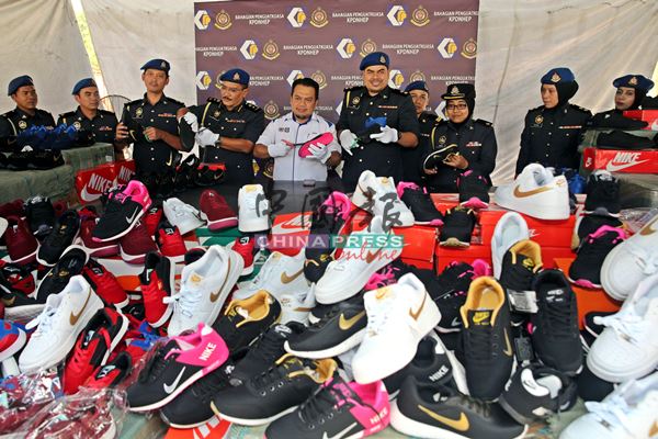 莫哈末兹克里阿占（左5）与贸消局执法员动用剪刀，剪破在检举行动起获的国际名牌仿冒运动鞋。