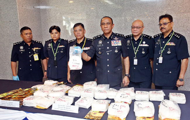 莫哈末卡里尔(右3)展示警方起获的各种类毒品。