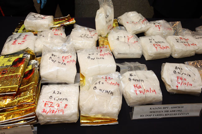 莫哈末卡里尔(右3)展示警方起获的各种类毒品。