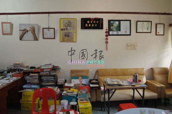邓日才住家客厅除了堆满的书及报纸，墙上也挂满了多张奖状，肯定他对华教的贡献。