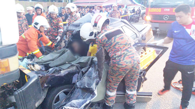 消拯员将夹在轿车内的死者移出。