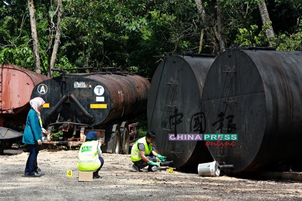 环境局官员从大油桶抽取样本。
