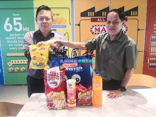 妈咪大宝达集团董事部副主席拿督朱国升（右）与本报甲州林钦为，展示送出的Mamee产品。