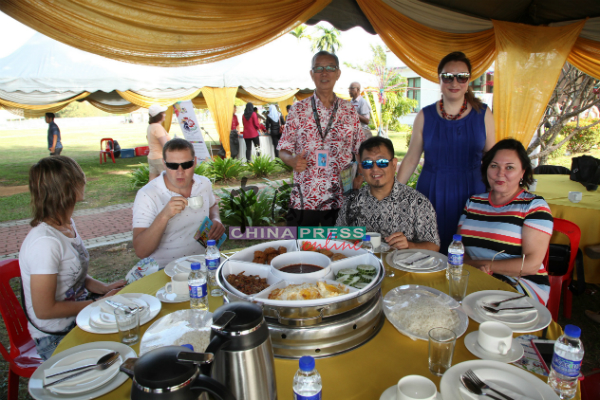 贾拉尼（坐者右2）大展热情一面，邀请游客们到主宾桌品尝马来传统美食。