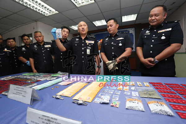 莫哈末卡马鲁丁（右3起）在李庆泉及多名警官陪同下，展示柔州肃毒组所起获的各类毒品和充公的财物。