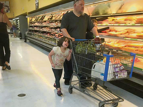 女孩的頭髮綁在超級市場的手推車。
