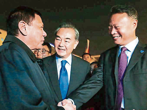 迪泰特（左）与迎接他的中国外长王毅（中）、中国驻菲大使赵鉴华（右）握手寒暄。 （中新网）