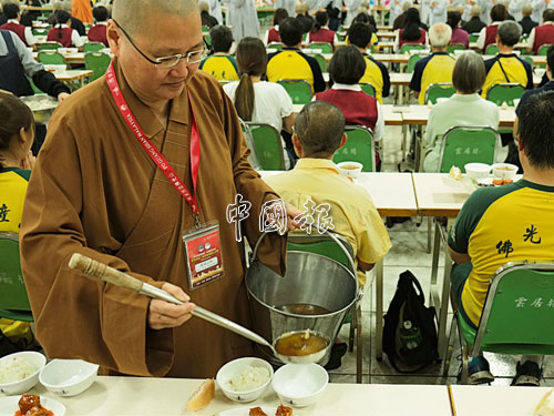 佛光山馬新泰印總住持覺誠法師，在「過堂」中為信徒派湯飯。 