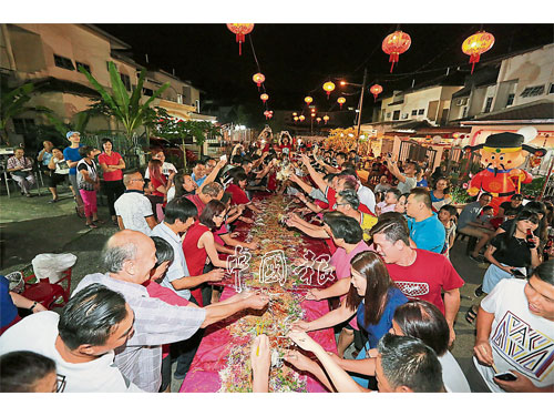逾百名居民聚集桌子周圍一起撈生，慶祝元宵節。