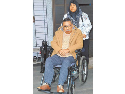 陳松勇（前）靠輪椅代步，由印尼看護Yule推他出門透氣。