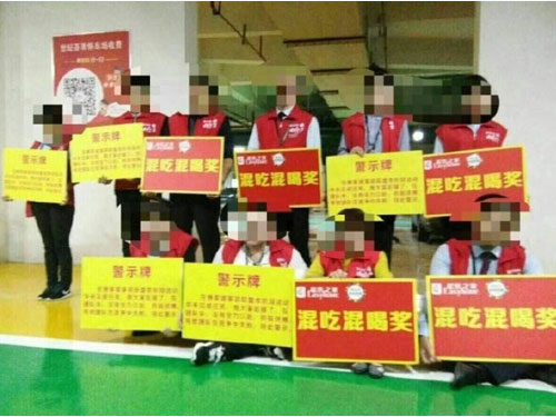員工被迫舉著寫有“混吃混喝獎”的紙牌拍照。圖/互聯網