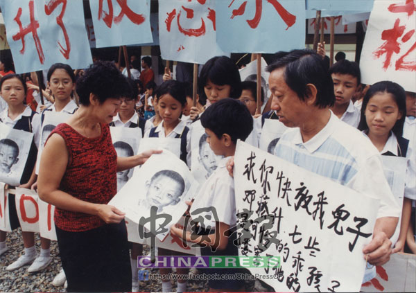 鄧桂林（右）與妻子（左）帶著大字報，前往小菘升就讀的小學發起尋人行動。