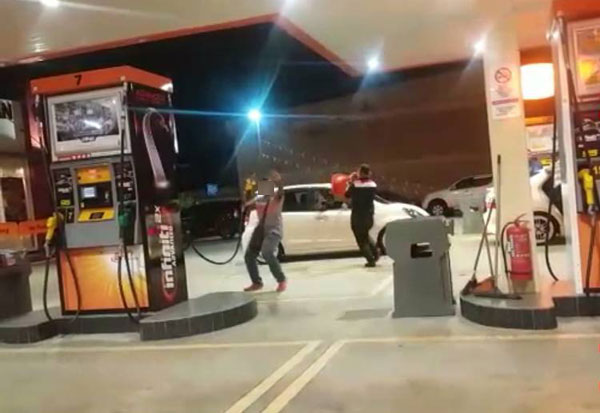 2名男子在油站各持油槍及3角錐在油站舞動，令人為之捏把冷汗。 