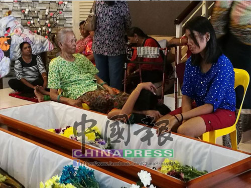 死者希哇勞的母親比麗瑪（坐者左起）、前妻及長女守在棺木旁。