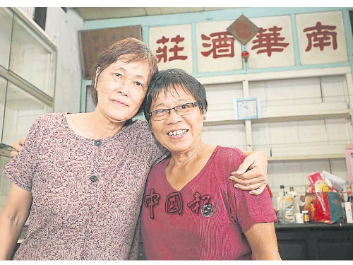 劉秀鳳（左起）與過去17年一同掌店的陳金美，在「南華酒莊」字眼前拍下合照。