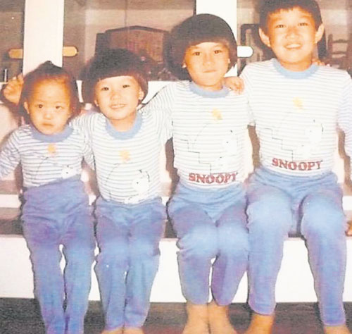 嬌小的妹妹和哥哥穿同款褲子、藍條紋上衣，一起看鏡頭。