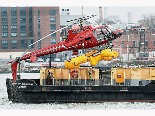  搜救當局動用一艘水上起重機，把墜毀的直升機打撈上岸。（美聯社）