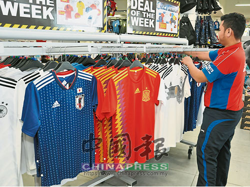  SportsDirect.Com店員，把世界杯足球賽熱門捧杯球隊的球衣上架。