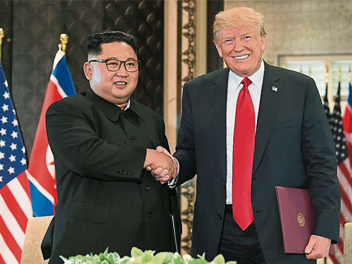  金正恩（左）和特朗普周二在簽署美朝聯合聲明文件后，兩人握手表示友好。（法新社）