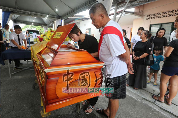 死者的二女儿杨雪梅在盖棺前见父亲最后一面，忍不住眼眶泛红，忍住泪水与父亲道别。