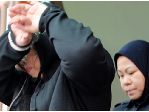 失信公款需监禁8年的被告，被女警押离法庭时以手臂遮挡脸孔。