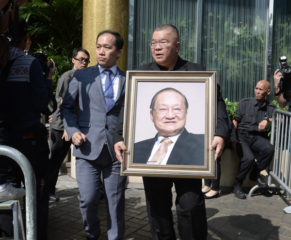 大殓仪式后,金庸儿子查传倜手持父亲遗照步出殡仪馆。