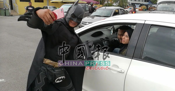 一对巫裔男女开车经过，看到“蝙蝠侠”现身，要求一起拍照。