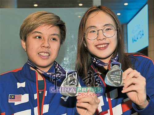 杜依蔚（左）和陈康乐展示世青赛女双银牌。